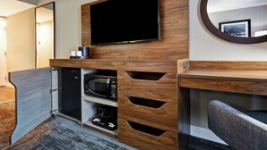 A modern hotel room with a flat-screen TV mounted on a wooden wall, a built-in microwave, and a coffee machine in a cabinet. - Hampton Inn I-75 Lexington/Hamburg Area (Lexington)