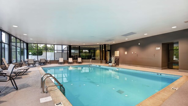 An indoor swimming pool with clear glass walls, lounge chairs, and a ceiling with recessed lighting. - Hampton Inn I-75 Lexington/Hamburg Area (Lexington)
