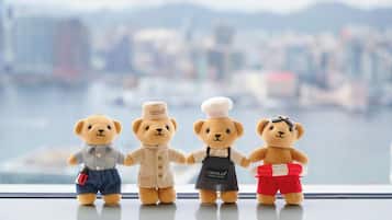 Four teddy bears on a windowsill with a cityscape view.