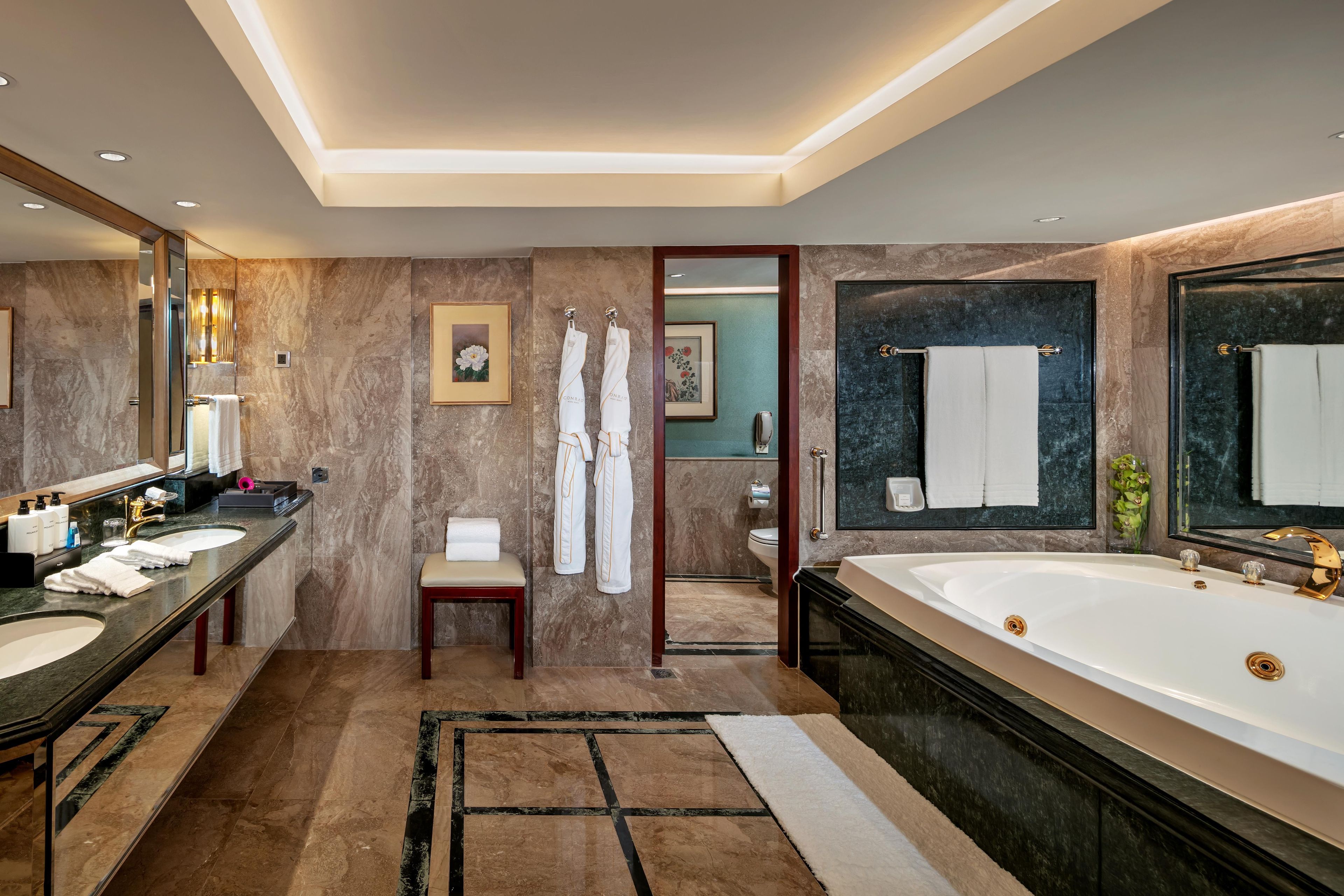 A modern bathroom with two sinks, a large bathtub, and a mirror.