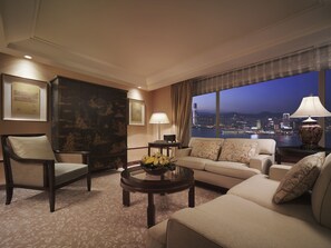 A modern living room with a sofa, armchairs, a coffee table, and a view of a cityscape at night. - Conrad Hong Kong (Hong Kong)