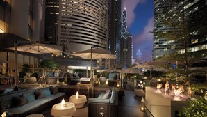 A rooftop lounge with outdoor seating, ambient lighting, and a view of city buildings. - Conrad Hong Kong (Hong Kong)
