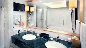 A modern bathroom with two sinks, a large mirror, a TV, and a shower.