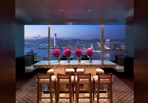 A modern dining area with a panoramic city view, a marble table, and six chairs. - Conrad Hong Kong (Hong Kong)