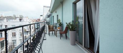 A balcony with a table and chairs, a potted plant, and a view of the cityscape.