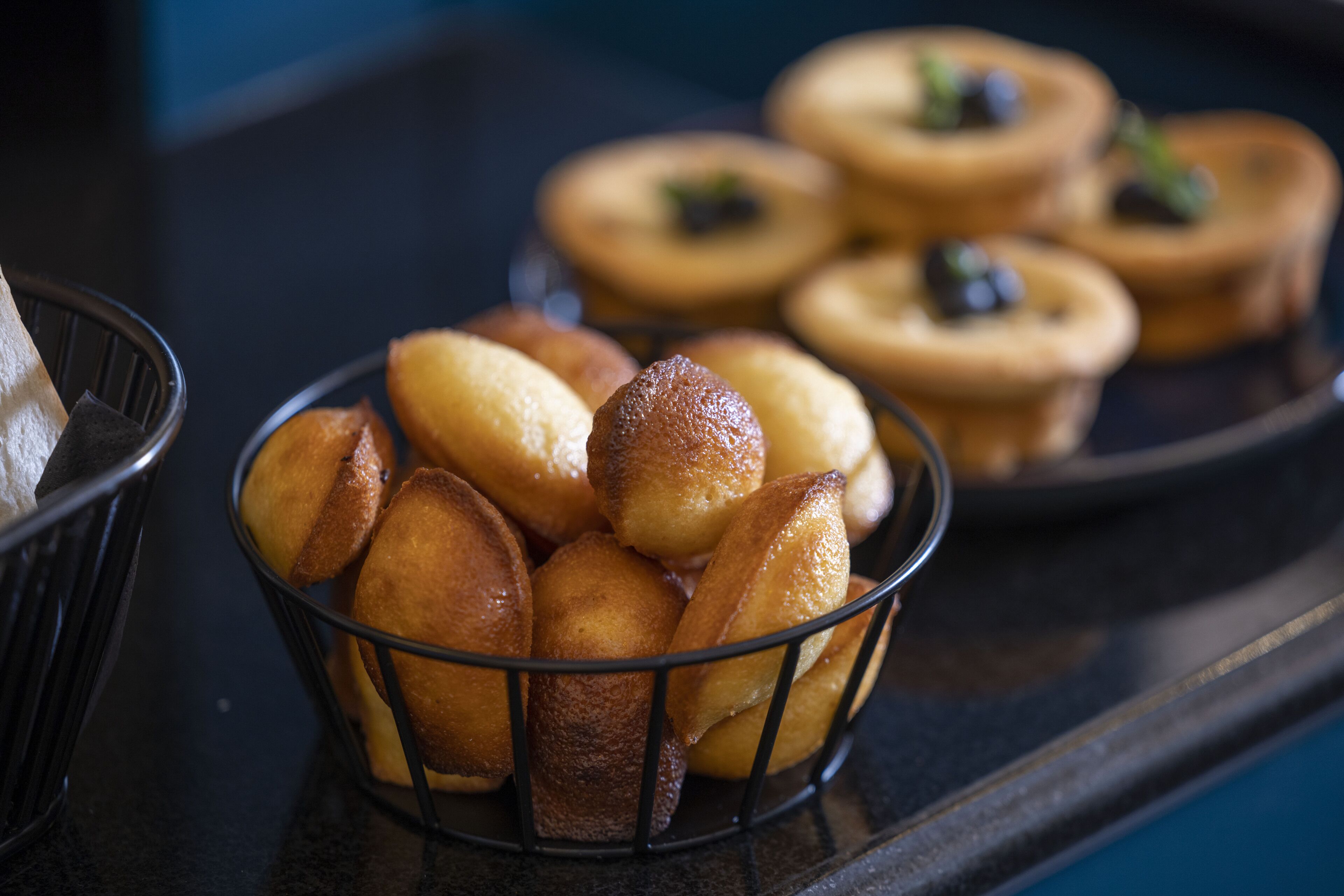 Une assiette remplie de diverses pâtisseries, notamment des tartes et des tartes à la crème, posée sur un comptoir sombre.