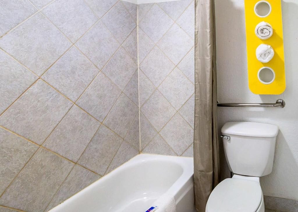 Un baño con bañera, inodoro y un toallero amarillo con tres toallas.