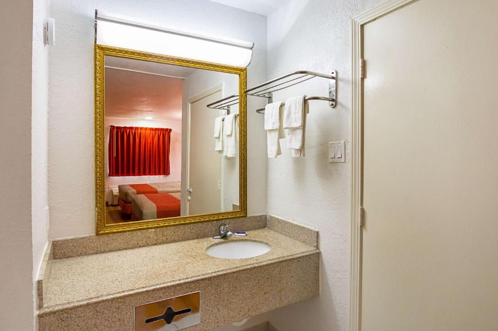 Un baño con lavamanos, espejo, toallero y puerta.