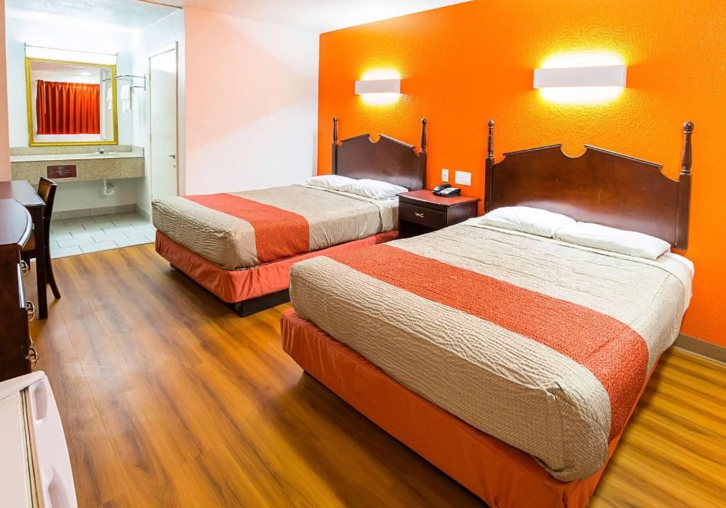 A hotel room with two beds, a desk, and a chair.