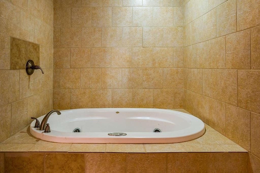 Ein Badezimmer mit einer freistehenden Badewanne, einer Wandbrause und einem gefliesten Boden.