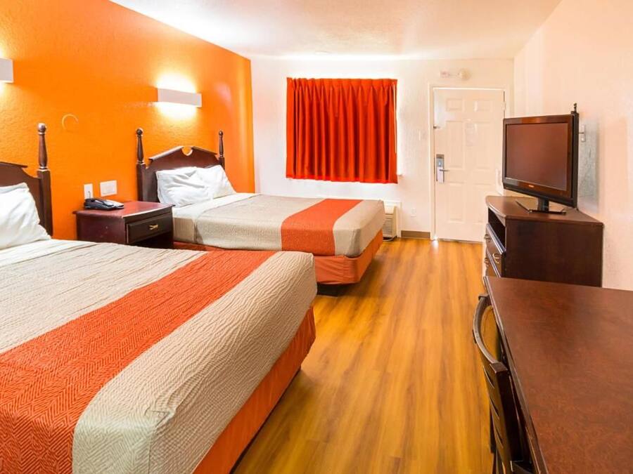 A hotel room with two beds, a television, and a door.
