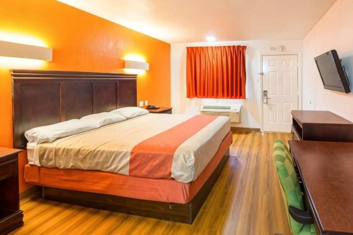 Een hotelkamer met een groot bed, een bureau, een stoel en een televisie aan de muur.