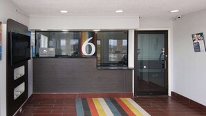 Un área de recepción moderna con un cartel grande con el número 6, una puerta de cristal y una alfombra a rayas.