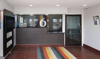 Un área de recepción moderna con un cartel grande con el número 6, una puerta de cristal y una alfombra a rayas.
