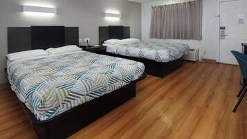 A hotel room with two beds, a desk, and a chair.