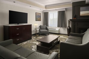 A hotel room with a flat-screen TV, a sofa, a chair, a coffee table, a lamp, and a fireplace. - Doubletree by Hilton Hotel Leominster (Leominster)