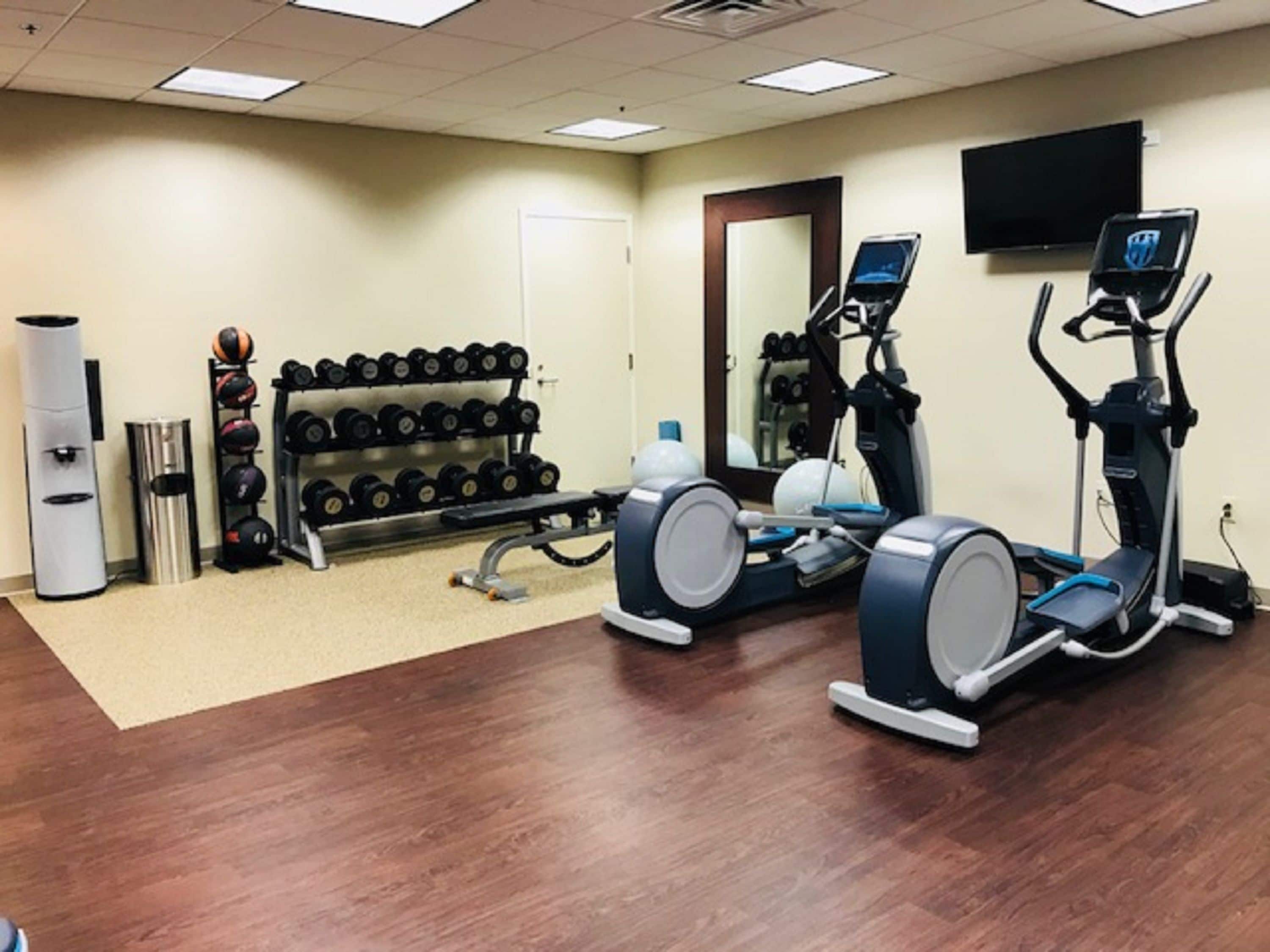 A gym with treadmills, a stationary bike, and a rack of dumbbells.