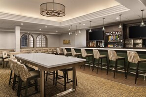 A bar area with a long counter, multiple bar stools, and a wall-mounted liquor dispenser labeled 'NECTAR'. - Doubletree by Hilton Hotel Leominster (Leominster)