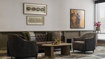 Ein modernes Wohnzimmer mit einem Ecksofa, zwei Sesseln, einem Couchtisch und Kunstwerken an den Wänden.