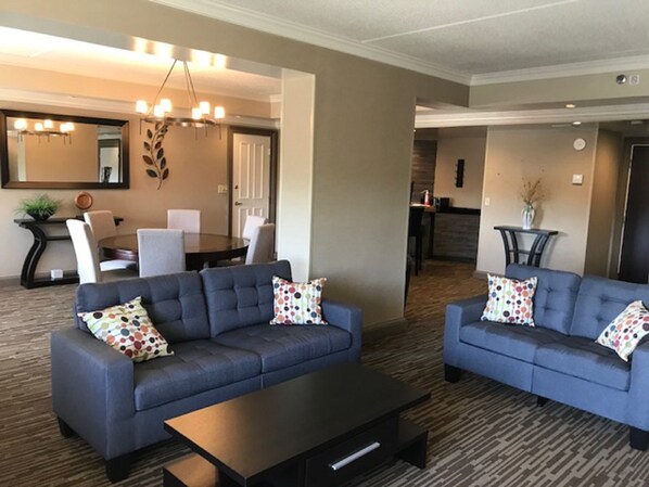 A modern living room with two sofas, a coffee table, and a dining area with chairs and a table. - Doubletree by Hilton Hotel Leominster (Leominster)
