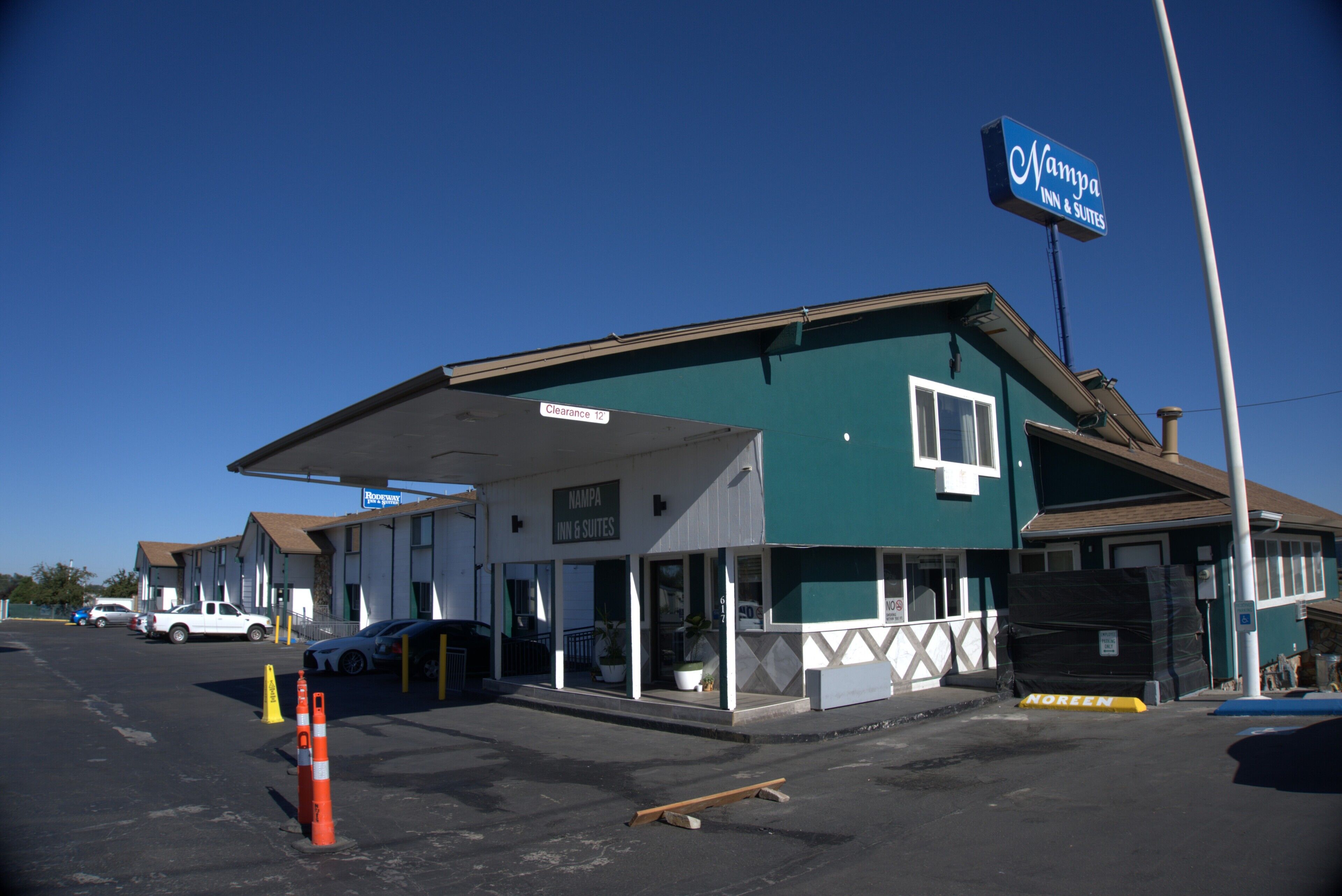 A motel with a clear sign, a covered parking area, and a building with a green facade.