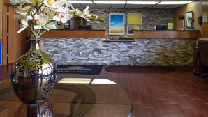 A reception area with a stone mosaic wall, a reception desk, and a vase of orchids on a glass table.