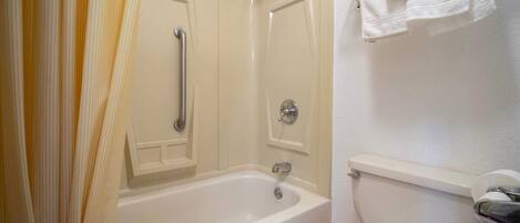 A bathroom with a bathtub, toilet, and a towel rack.