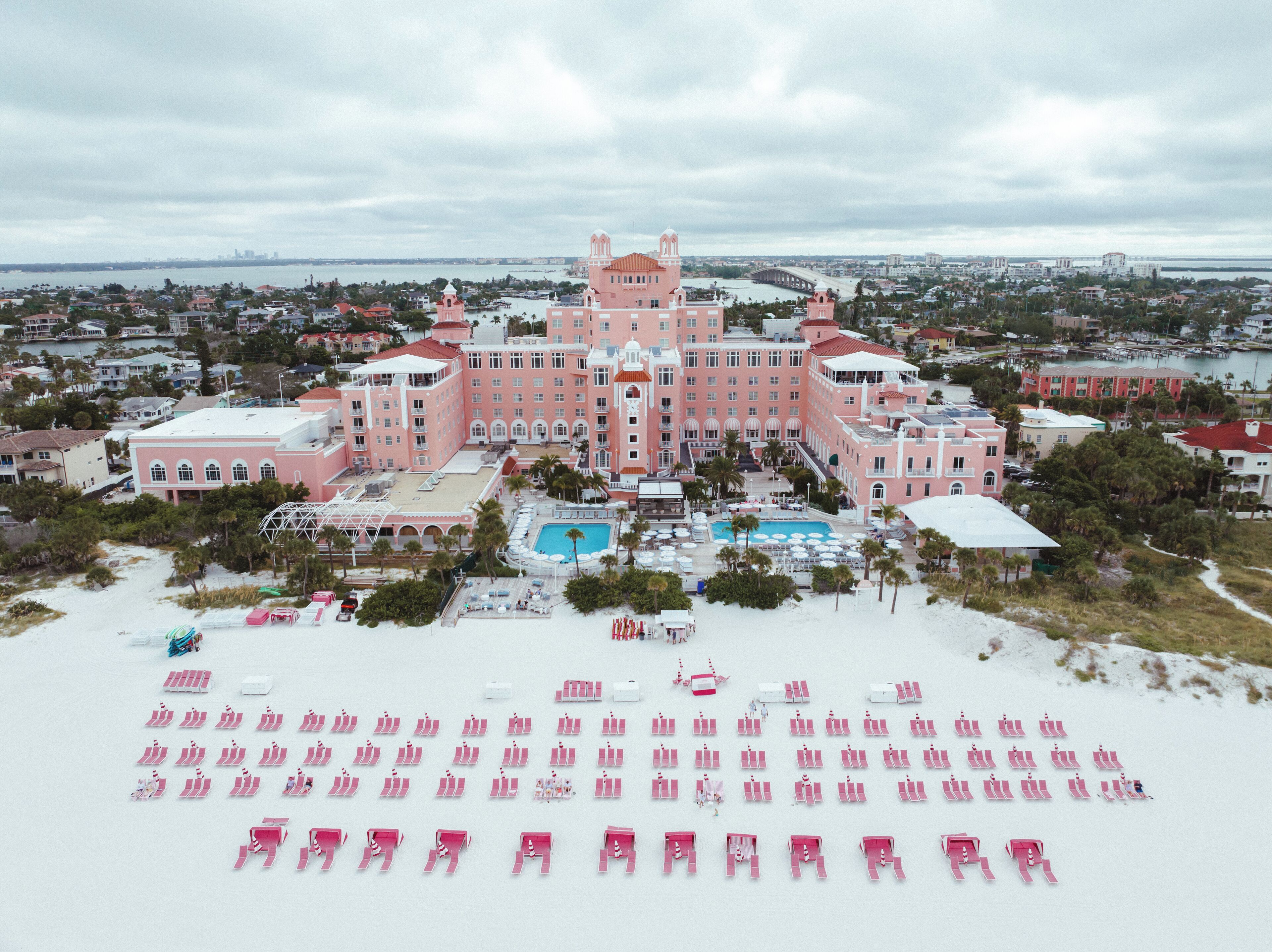 A large pink hotel with a central courtyard and a swimming pool.
