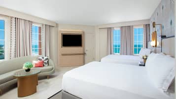 Habitación de hotel con sofá, dos camas, televisión y vista al océano.