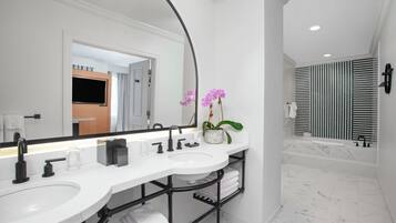 Une salle de bain moderne avec un meuble-lavabo blanc, des accessoires noirs et un grand miroir.