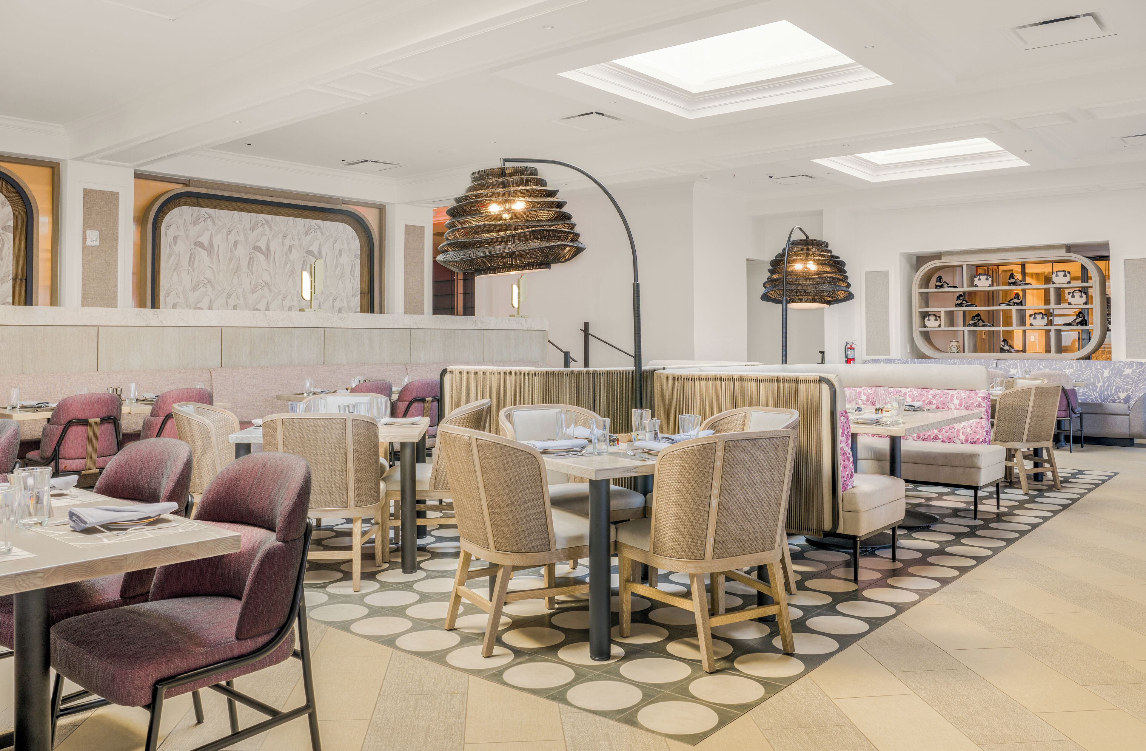 A modern restaurant with round tables, cushioned chairs, and a patterned floor.