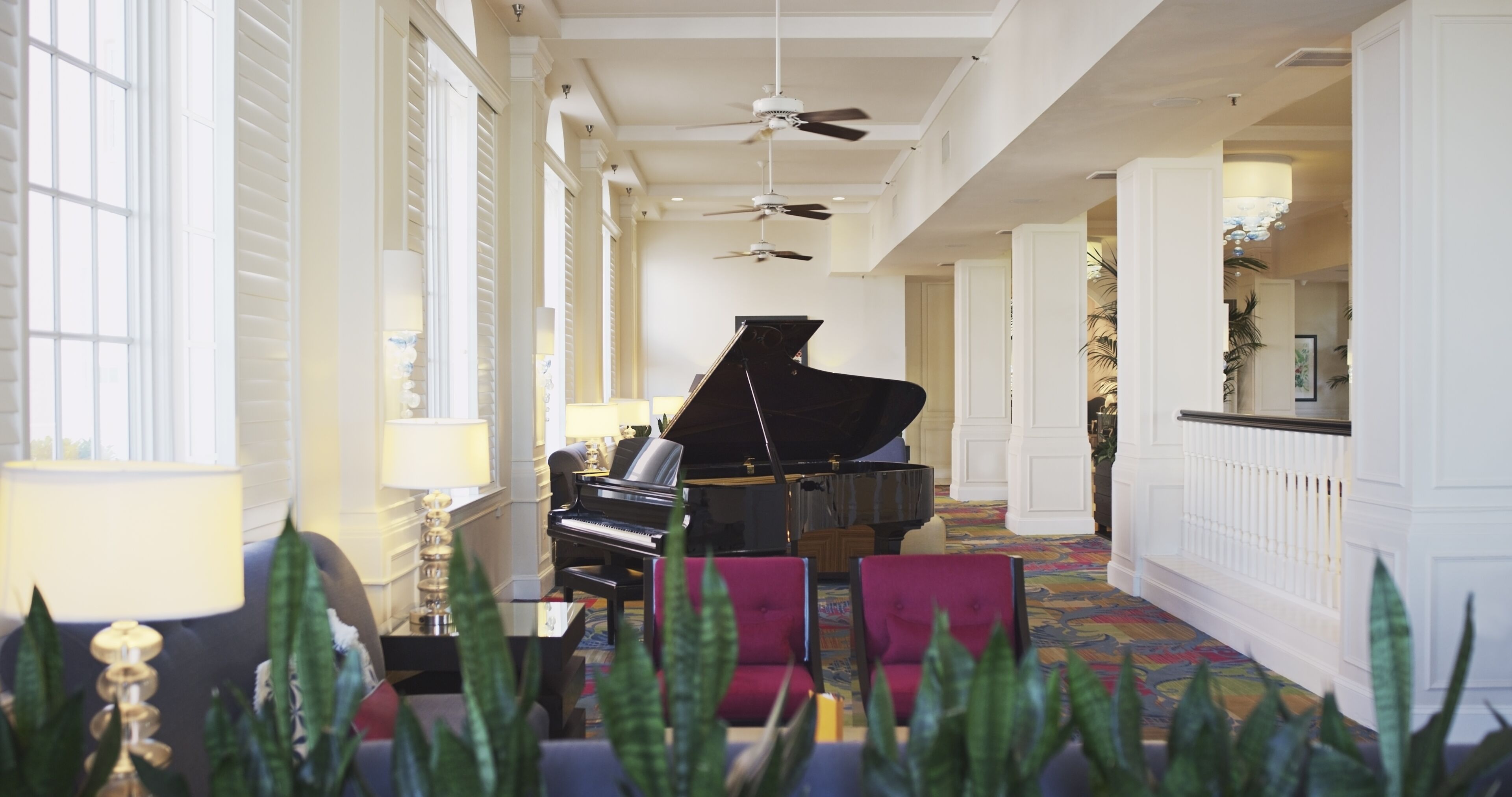 A grand piano in a spacious, well-lit lobby with high ceilings and large windows.