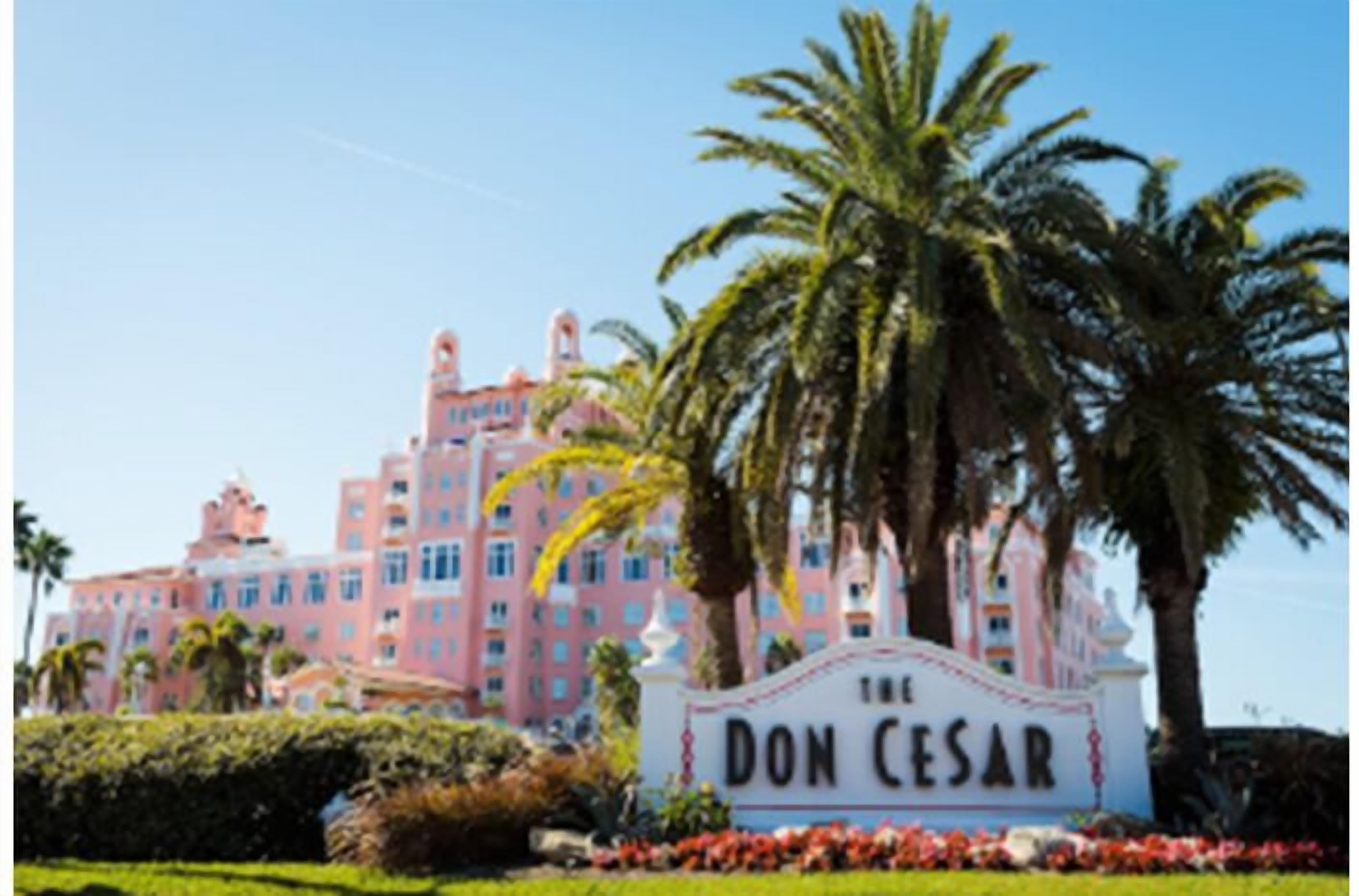 Un grand bâtiment rose, à plusieurs étages, sur lequel on peut lire l’inscription « The Don Cesar ».