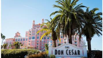 Un grand bâtiment rose, à plusieurs étages, sur lequel on peut lire l’inscription « The Don Cesar ».