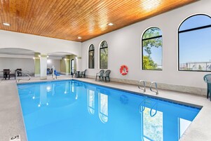 Una piscina con agua azul cristalina, rodeada de sillas y un flotador en la pared.