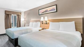 Una habitación de hotel con dos camas, una mesita de noche, una lámpara y un cuadro en la pared.
