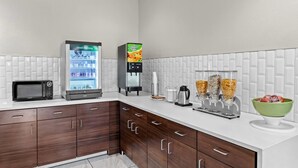 Una cucina moderna dotata di microonde, frigorifero, macchina da caffè e distributore automatico di caffè.