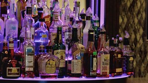 Una zona de bar con diversas botellas de licor y un refrigerador con botellas de cerveza.