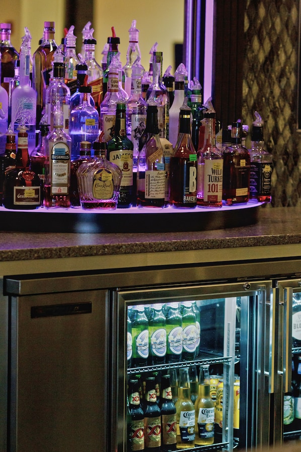 A bar area with various liquor bottles and a refrigerated display case with beer bottles.