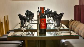 Mesa de comedor dispuesta con copas de vino, una botella y servilletas negras.