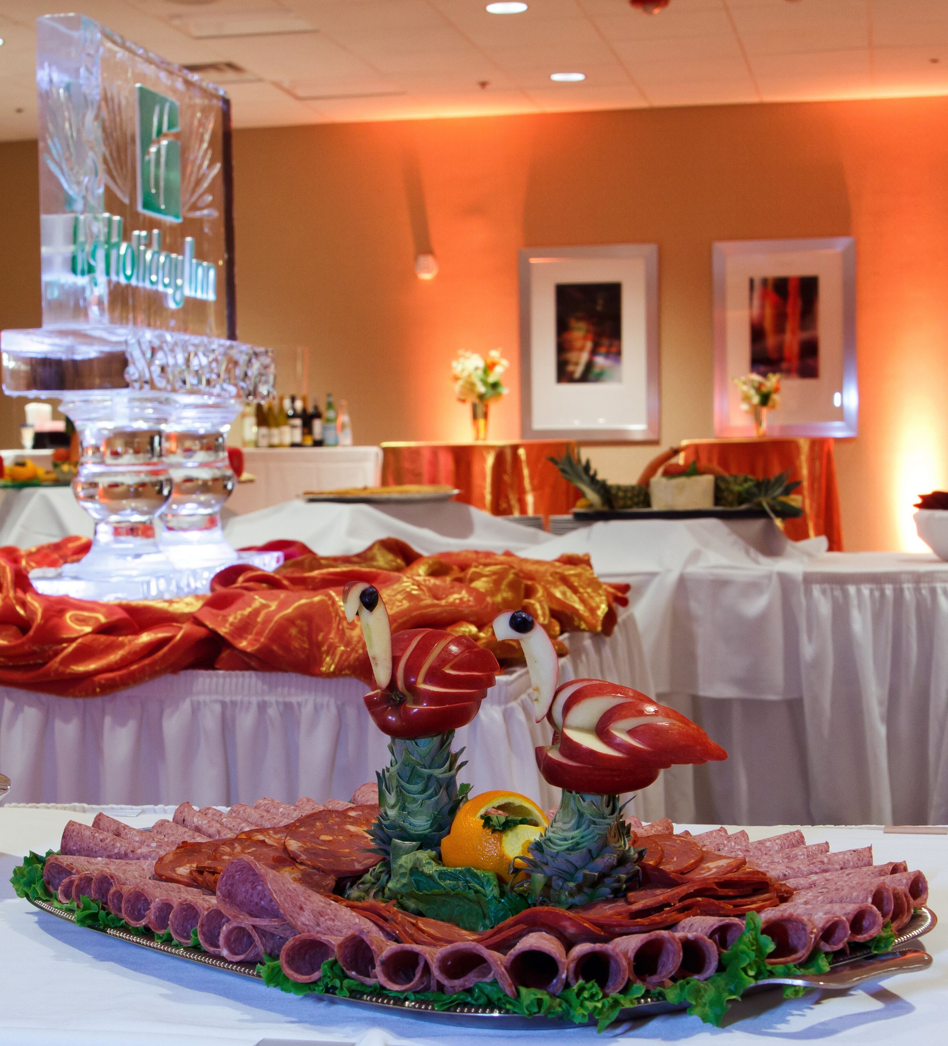 A buffet table with various food items, including a centerpiece with carved fruits and vegetables.