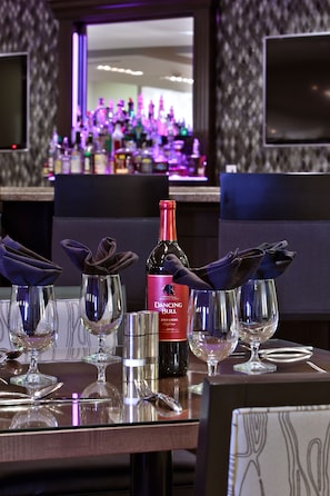 A bar area with a bottle of Dancing Bull wine, neatly arranged glasses, and a reflective surface. - Holiday Inn Charlotte Airport by IHG (Charlotte)