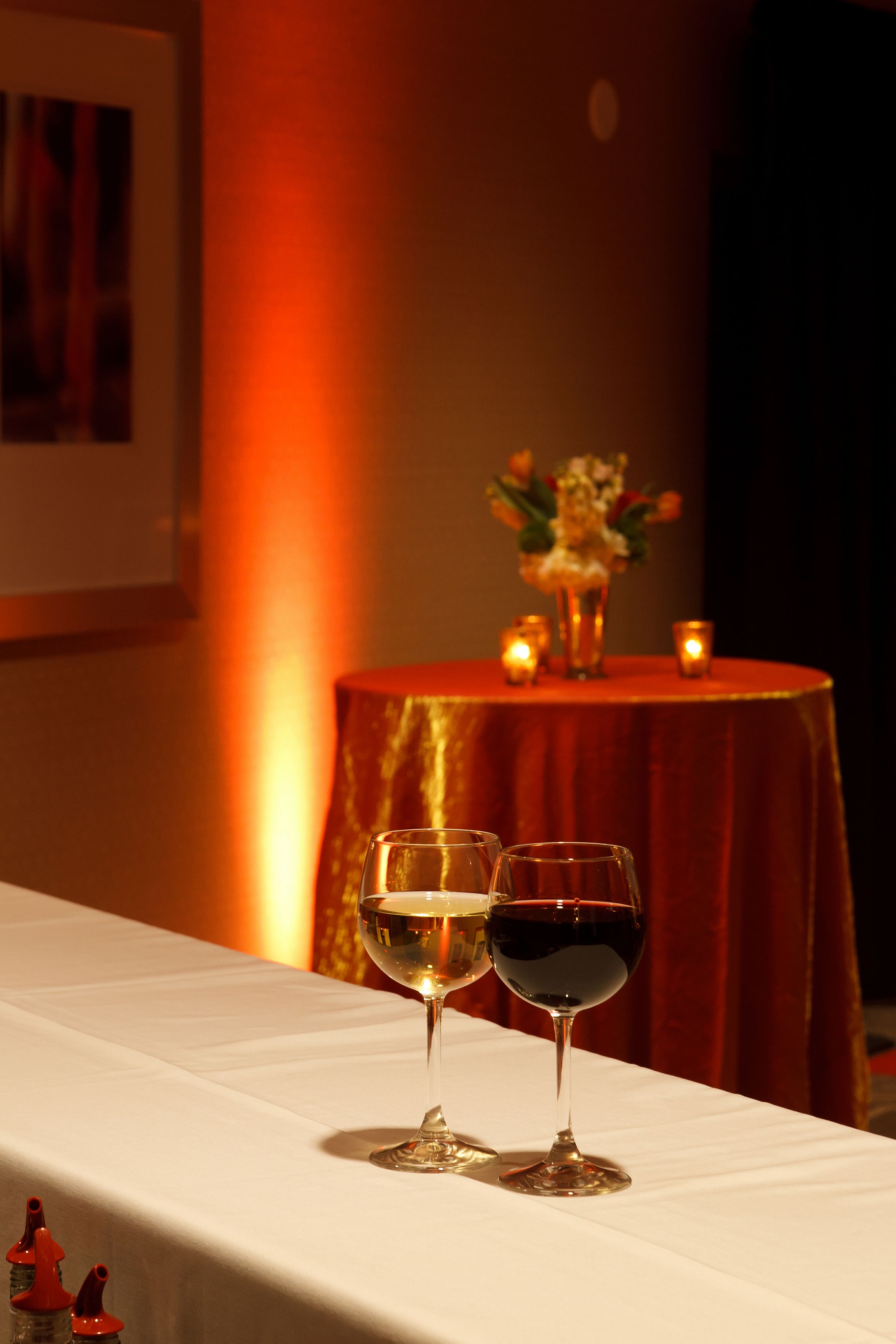 Una mesa con dos copas de vino, un florero con flores y velas.