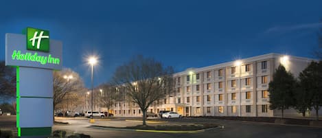 Señal de Holiday Inn con un edificio moderno al fondo.