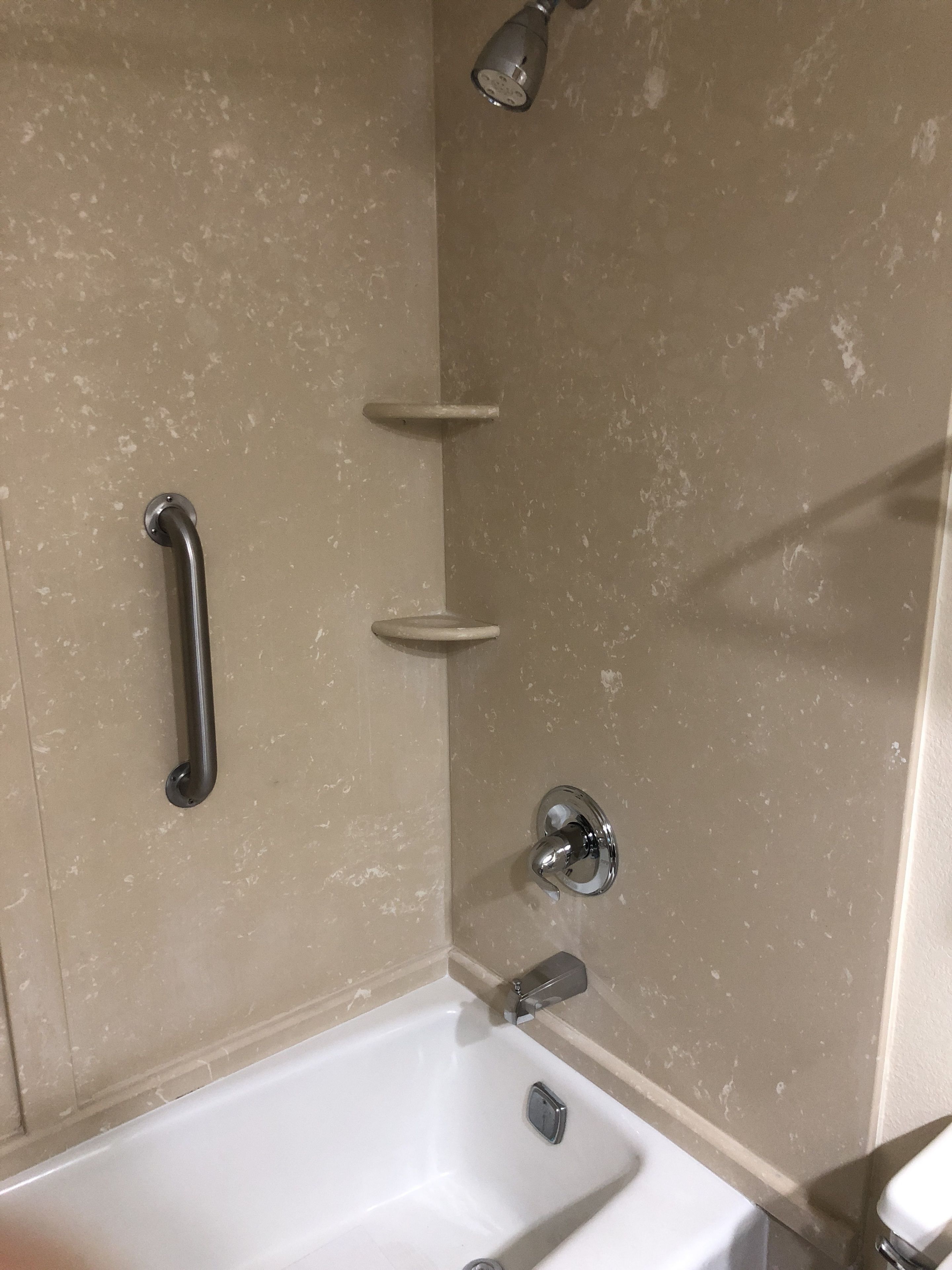 A bathroom with a bathtub, a shower, and a handrail.