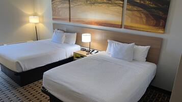 A hotel room with two beds, a nightstand with a lamp, and a painting on the wall.
