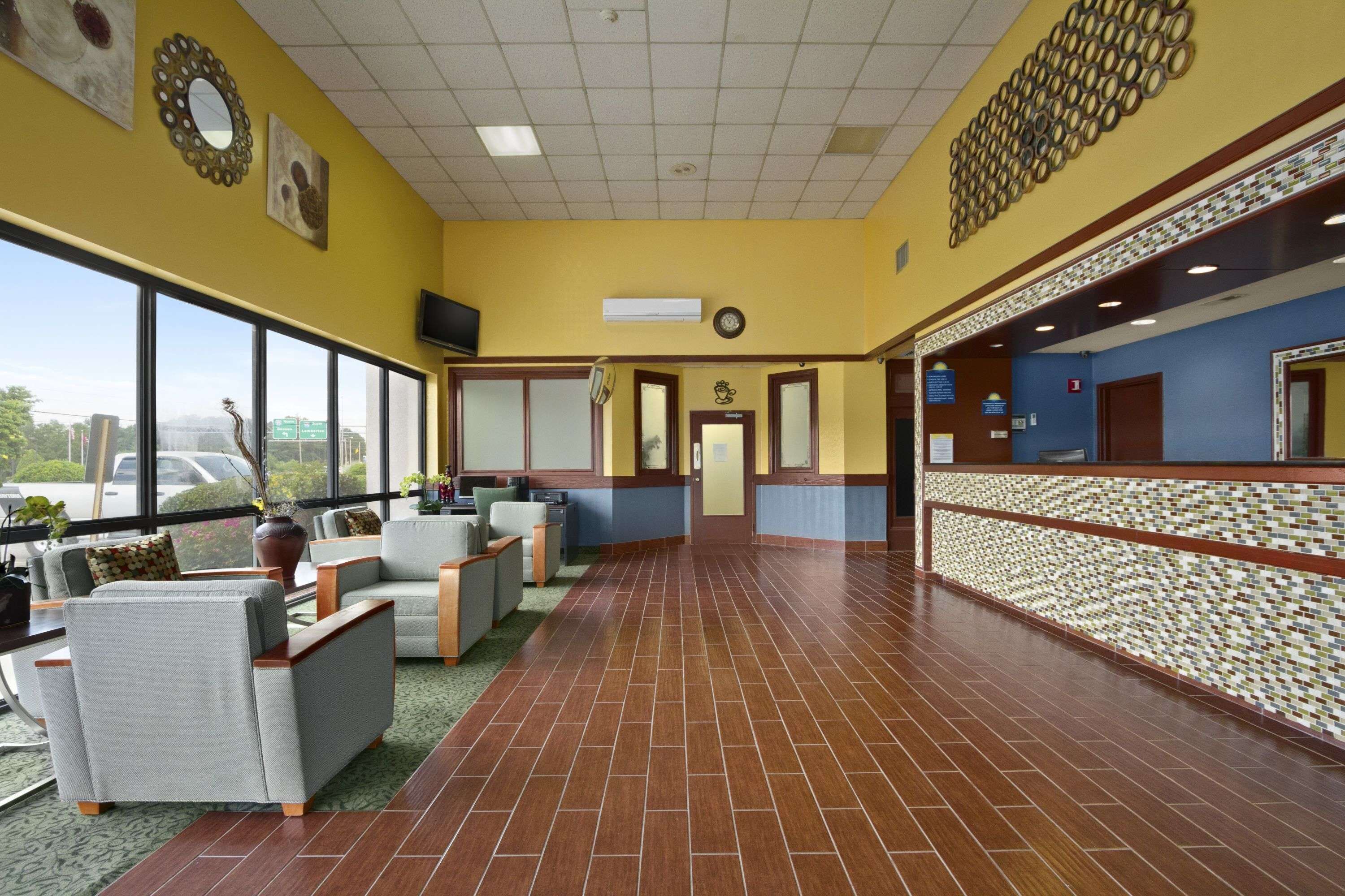 Een hotel lobby met een receptiebalie, een zithoek en grote ramen met uitzicht op buiten.