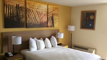 A hotel room with a large bed, two bedside lamps, a nightstand with a phone, and three wall-mounted paintings.