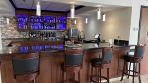 A bar area with a stone wall, multiple liquor bottles, and bar stools. - THE PARAGON of Golden Isles (Brunswick)