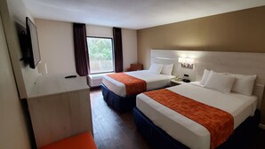 A hotel room with two beds, a TV, a desk, and a window with curtains. - THE PARAGON of Golden Isles (Brunswick)